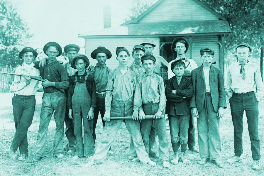 Promoting Your Community, showing a group of young men from the late 1800's standing together looking serious in front of an old house. 